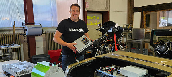 In dem Mercedes PagoClemens Hummel hält die elektronische Steuereinheit in der Hand. Auf dem Tisch liegt der grüne Elektromotor.