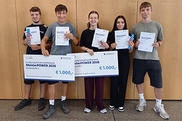 Gruppenbild: Drei Schüler und zwei Schülerinnen mit Urkunden und zwei großen Schecks in der Hand.